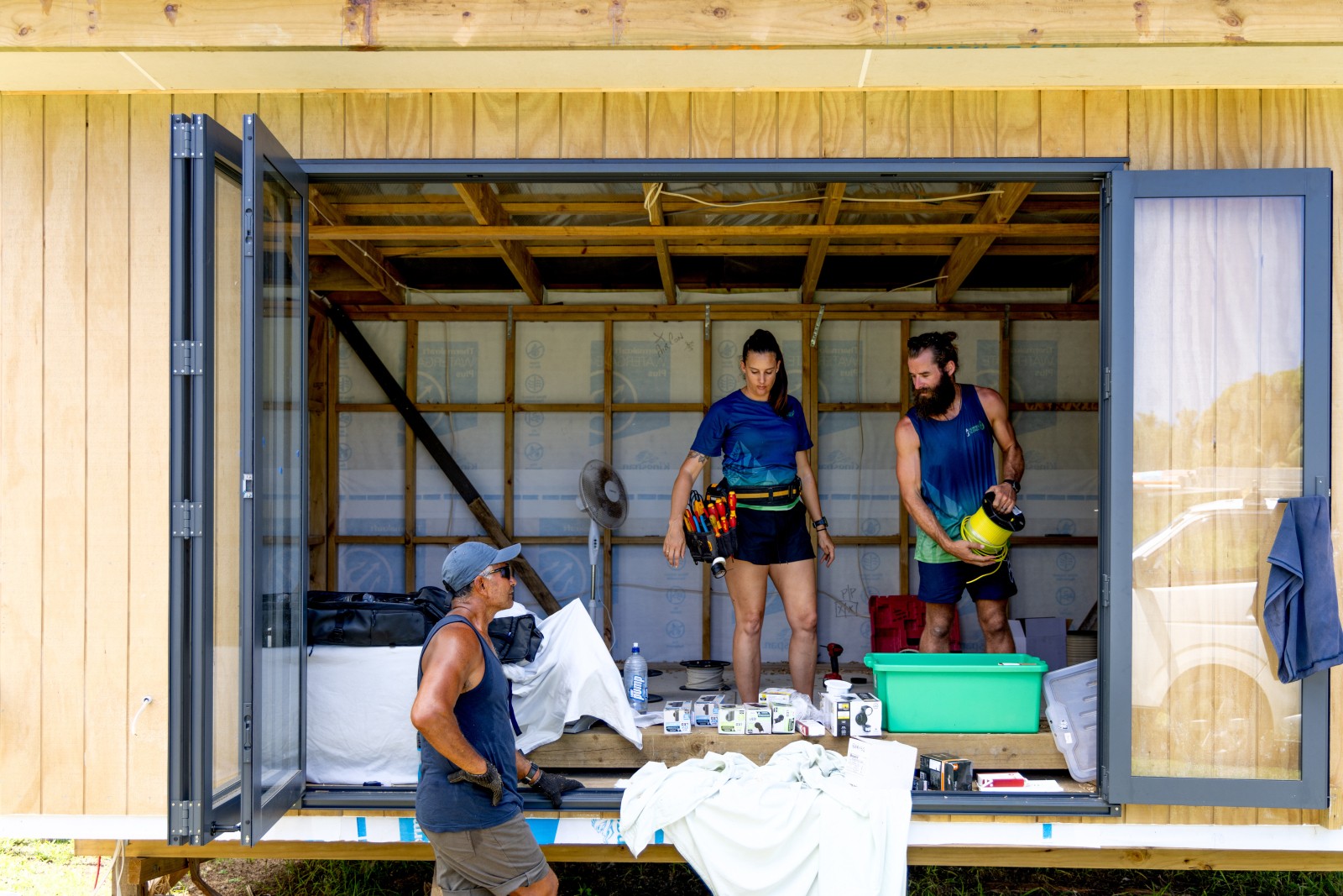 Electricians and a builder working together inside a timber-framed building